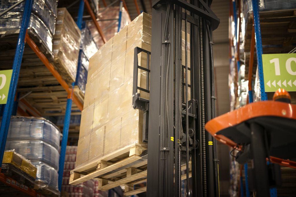 Industrial forklift machine lifting palette full of cardboard bo