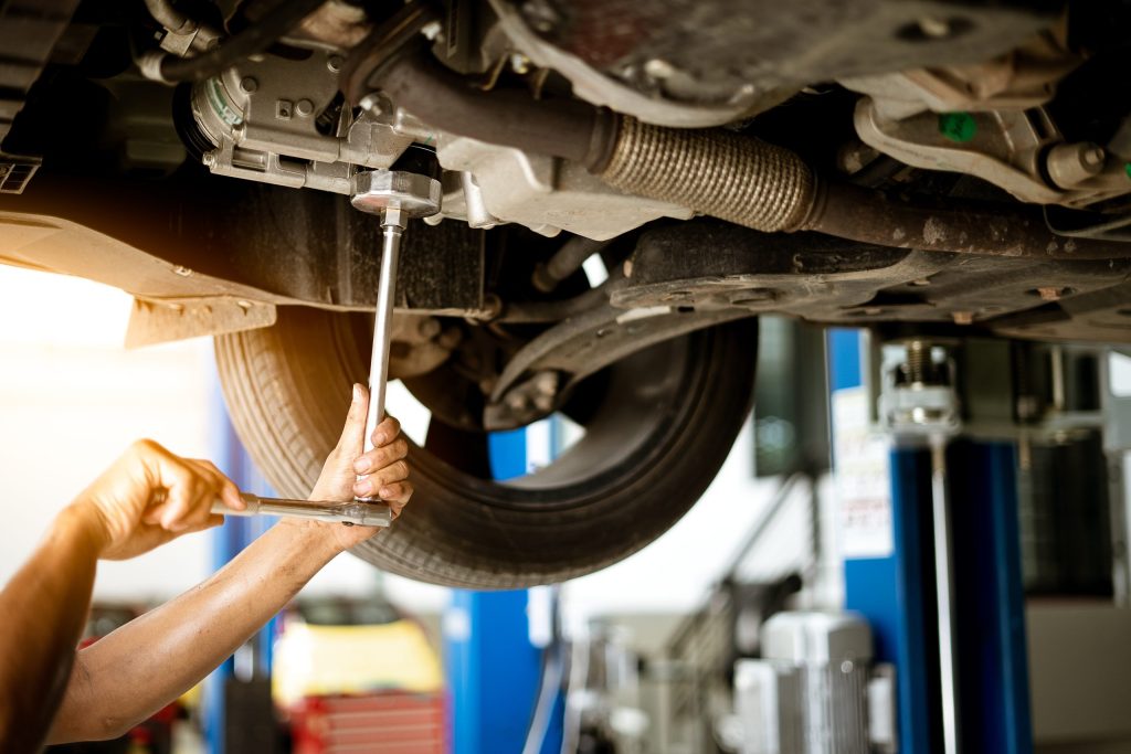 Mechanic is turning the nut to fix the car in the garage repair service scaled